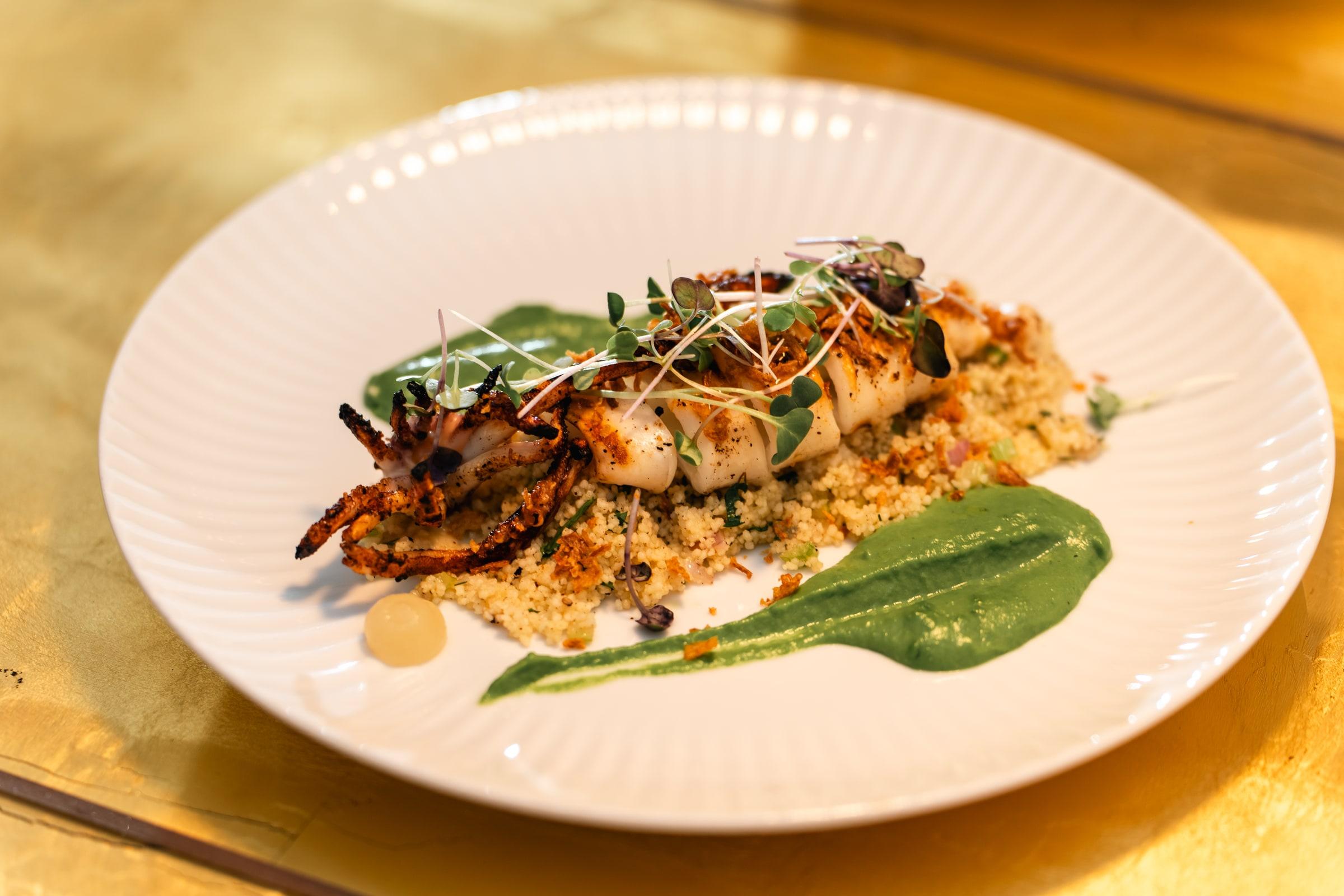 Grilled calamari on crumbled rusk with a sweep of green herb sauce