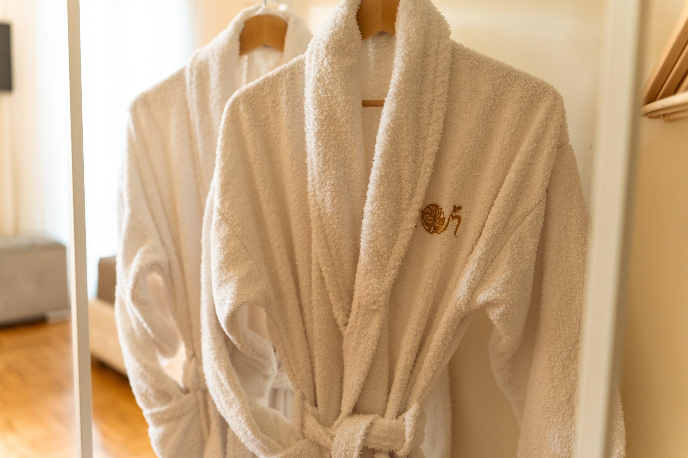 Embroidered bathrobes hanging in a suite